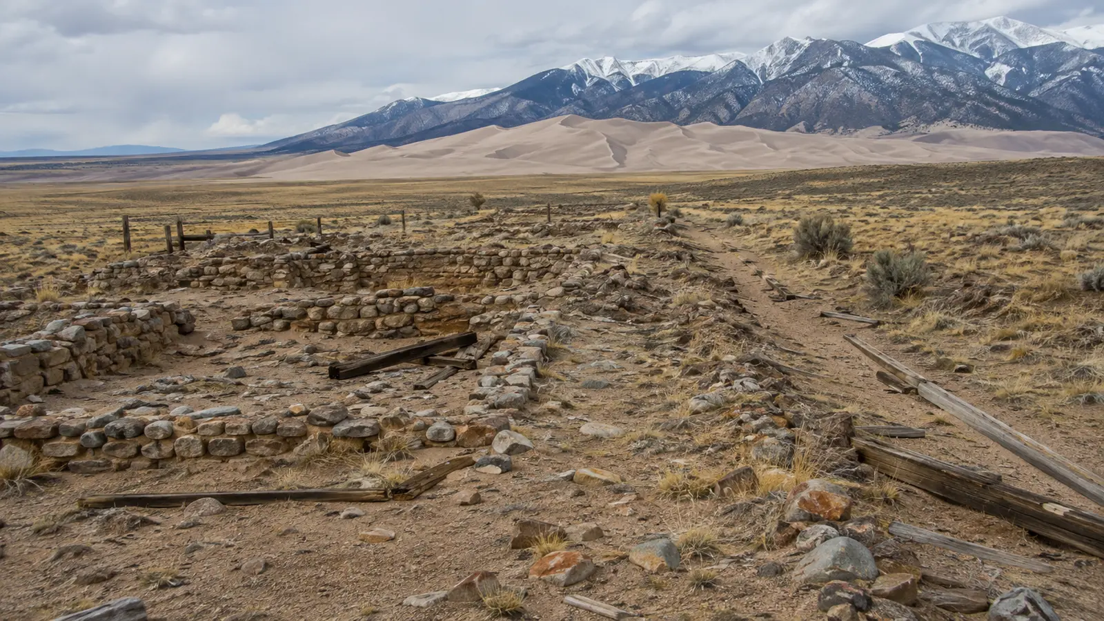 Scattered mining foundations and timbers in the high desert near the dunes